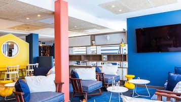 Un espacio lounge moderno con asientos, una estantería y un televisor.