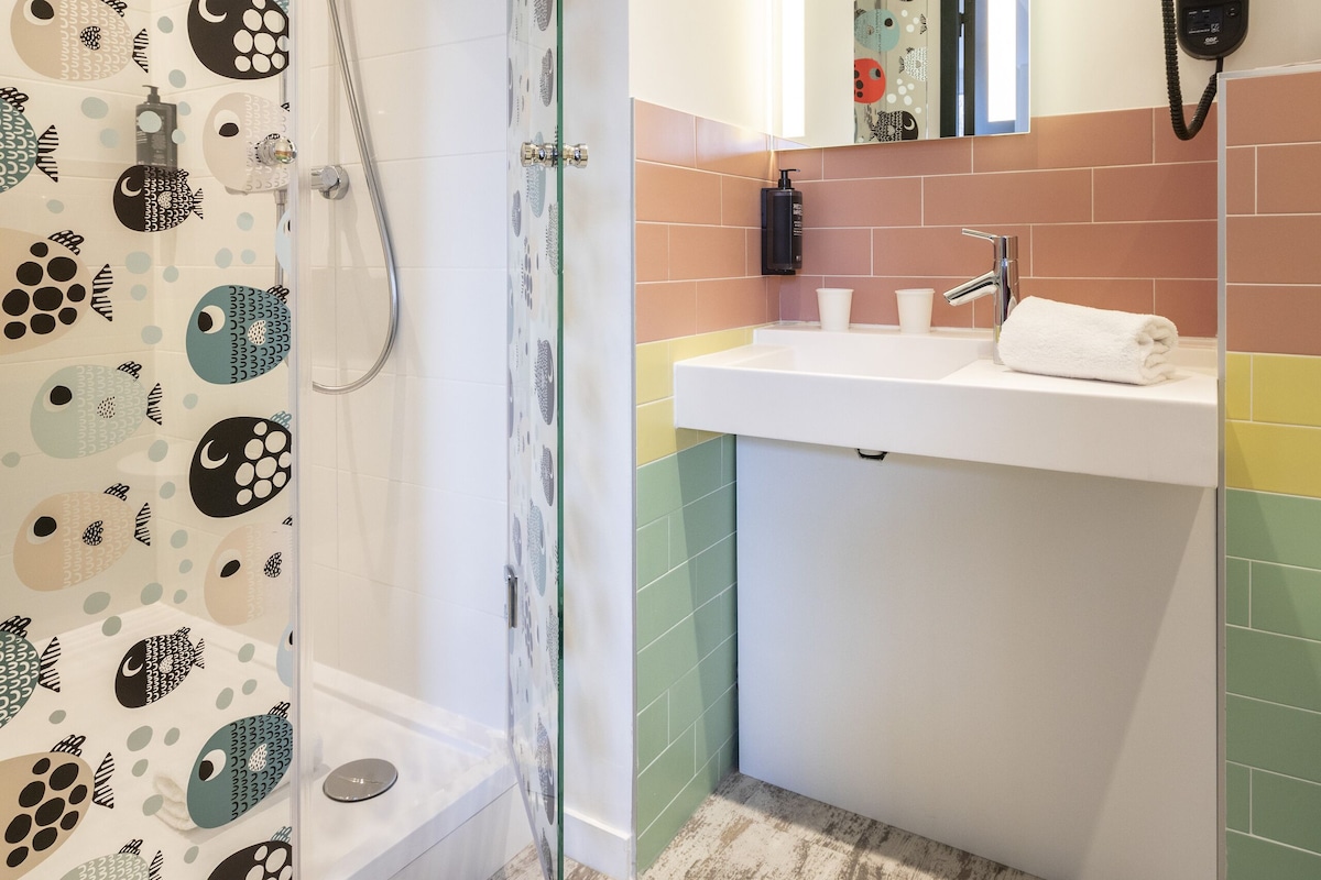 A bathroom with a glass-enclosed shower, a white sink with a mirror, and a towel on the counter.