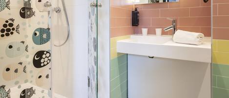 A bathroom with a glass-enclosed shower, a white sink with a mirror, and a towel on the counter.