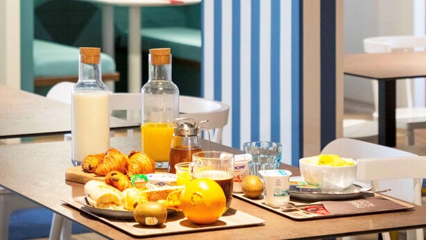 A breakfast table with croissants, orange juice, and a bowl of fruit. - ibis Styles Thonon Les Bains Hotel (Thonon-les-Bains)