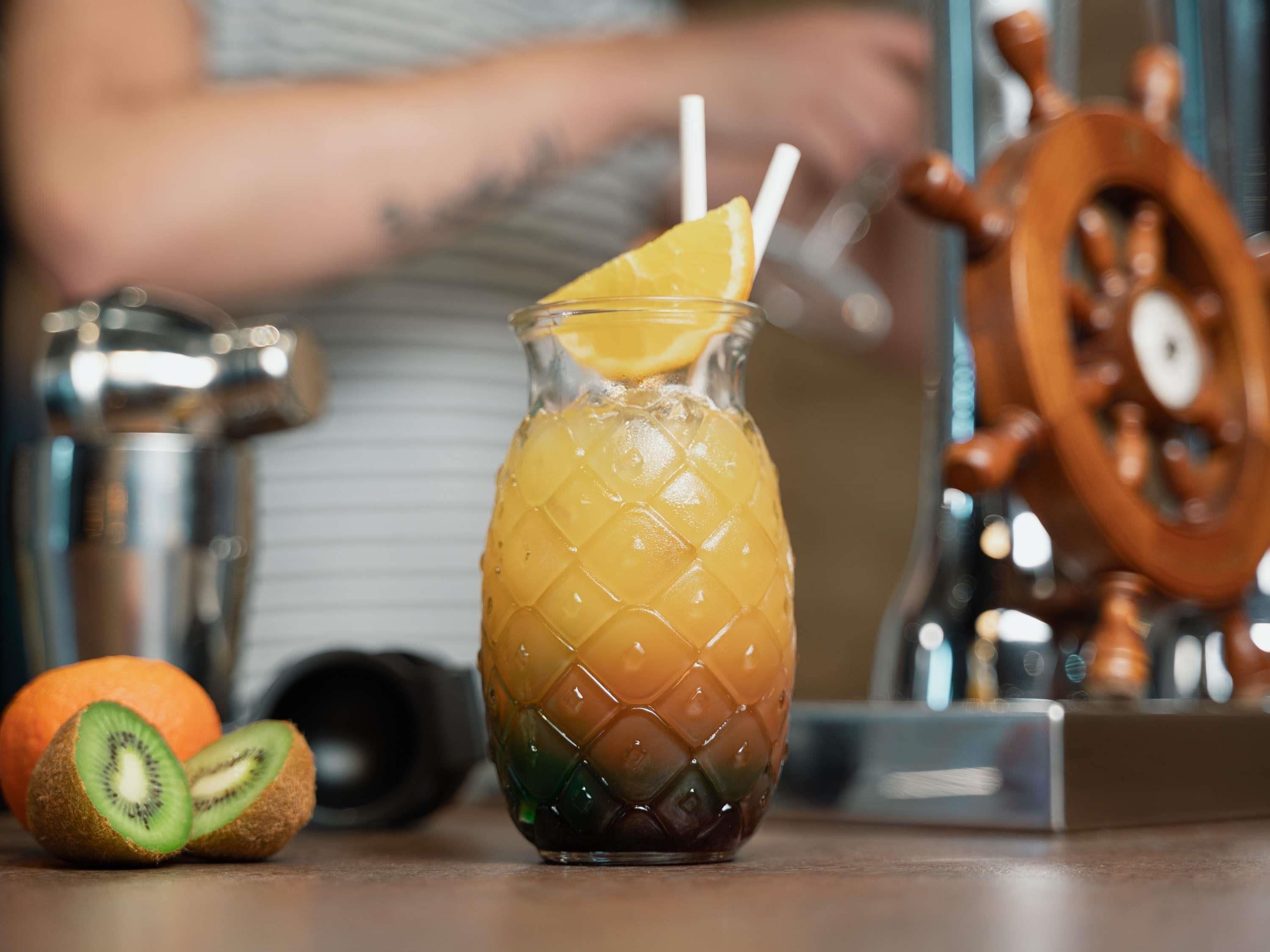 Un verre à motifs, une tranche d’orange et une moitié de kiwi posés sur une table.
