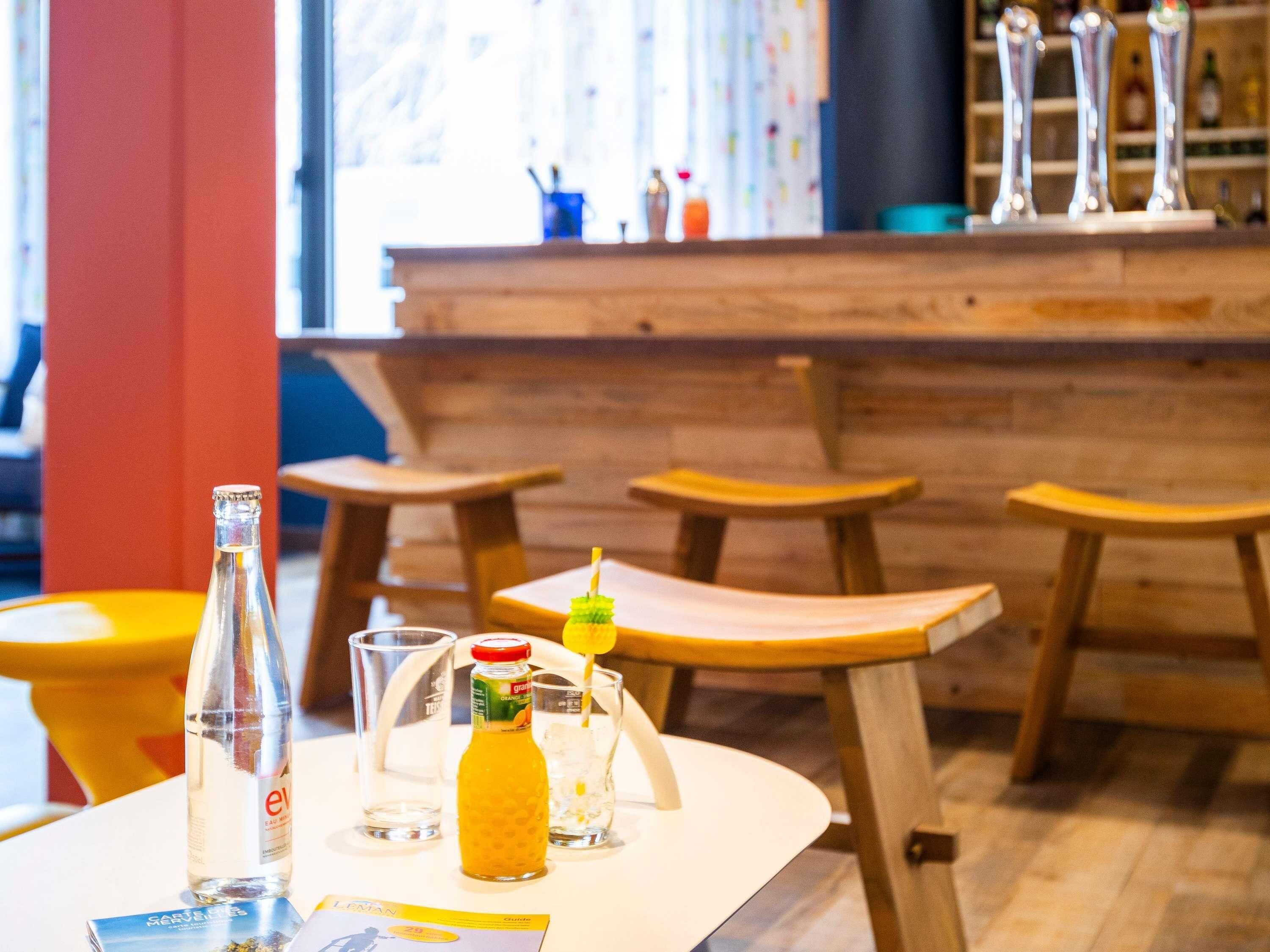 A bar area with stools, a bar counter, and bottles of beverages.