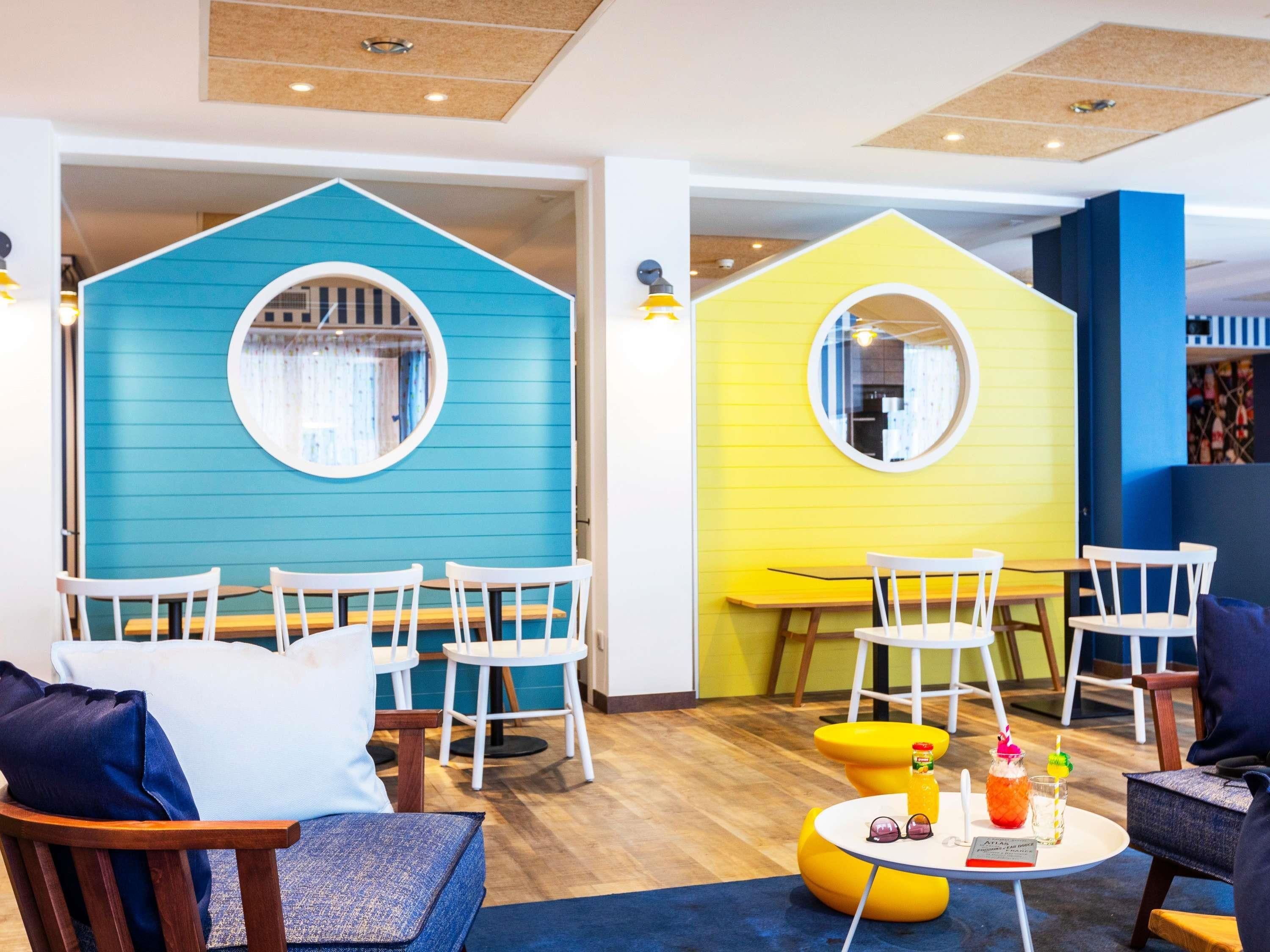 A children's play area with two house-shaped play structures, wooden tables, and white chairs.