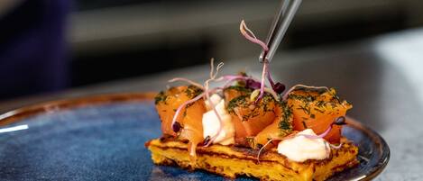 Un chef utilise une pince pour déposer une garniture sur un plat.