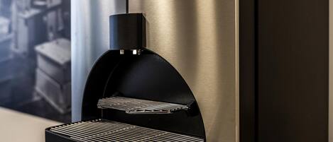Una máquina de espresso moderna con acabado metálico, integrada en una elegante pared de acero inoxidable.