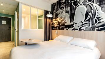 A modern hotel room with a large bed, a round table, and a wall mural.
