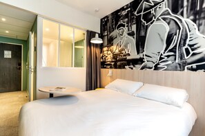 A modern hotel room with a large bed, a round table, and a wall mural. - ibis Styles Limoges Centre (Limoges)