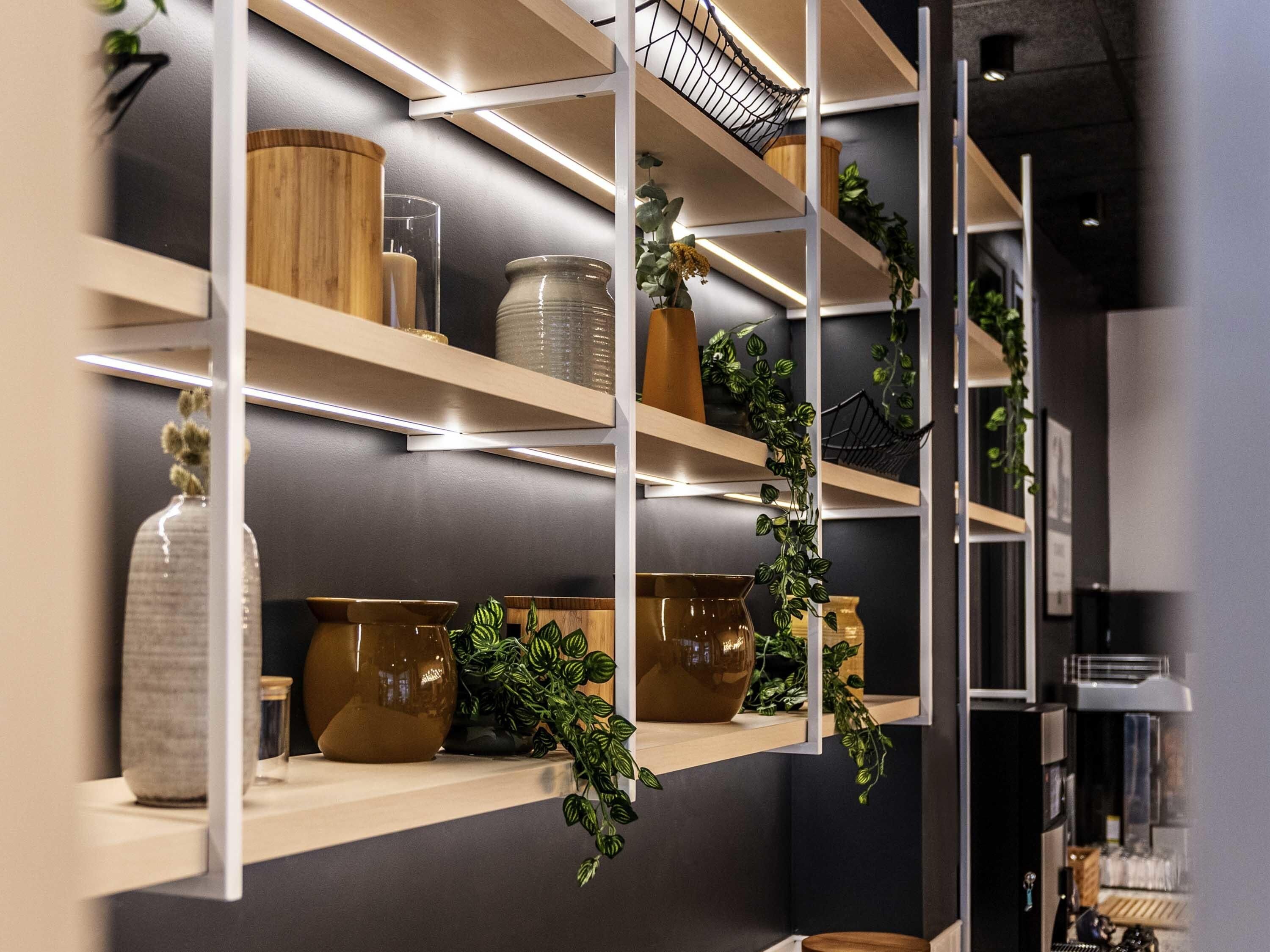 A modern kitchen with wooden shelves, a coffee machine, and various kitchen items.