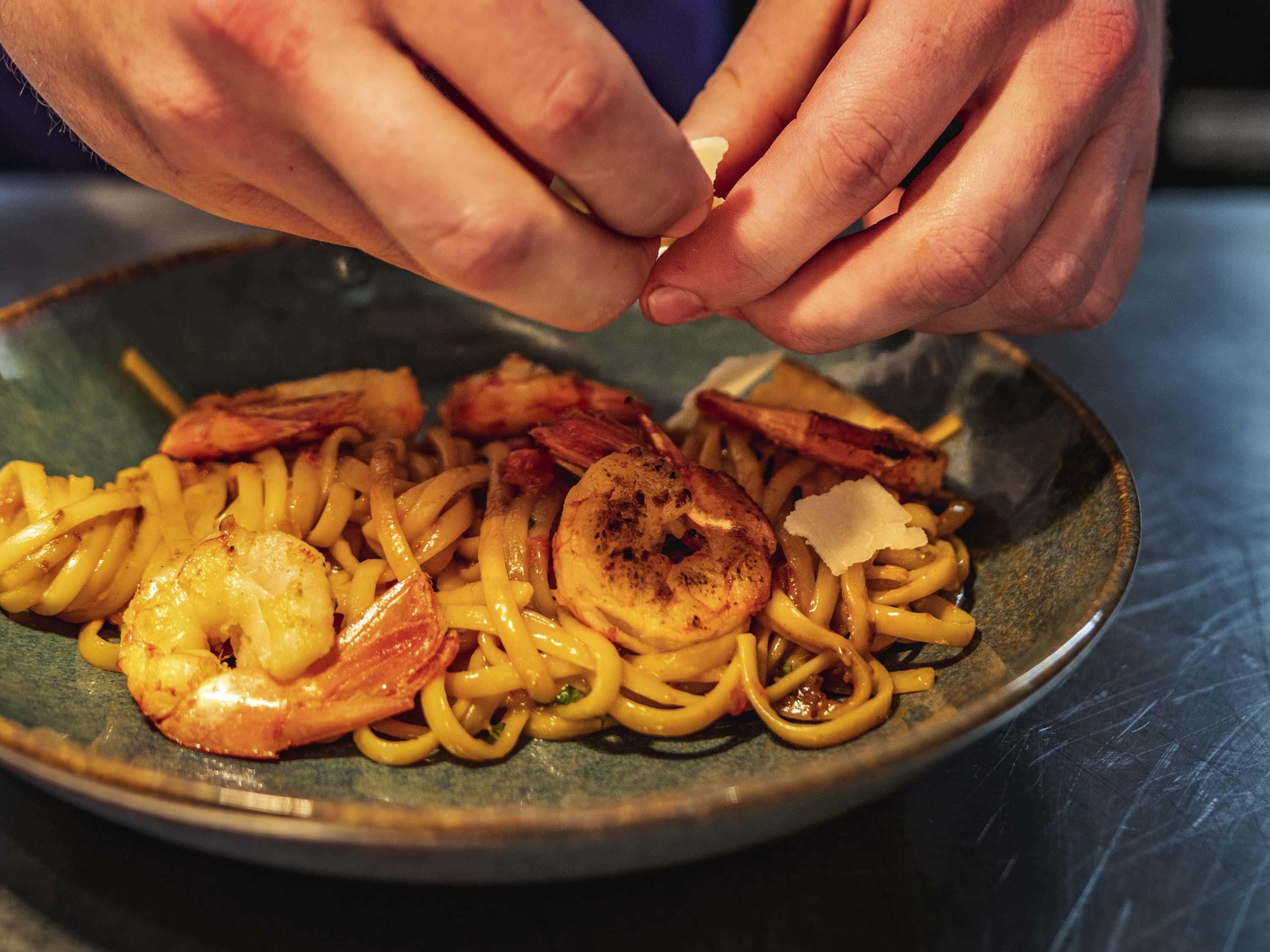 A plate of spaghetti with shrimp and bacon.