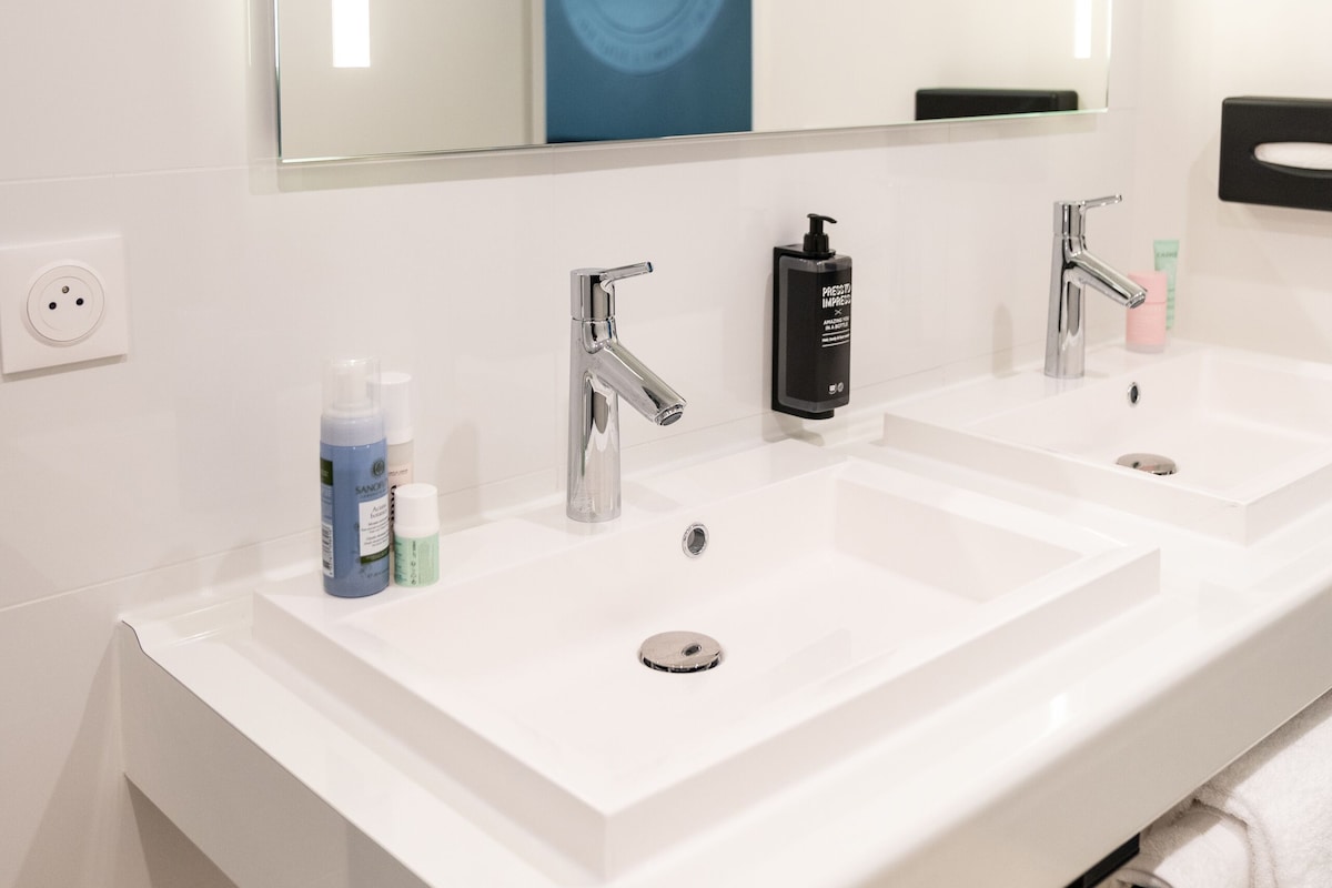 A modern bathroom with two sinks, a large mirror, and a towel rack.