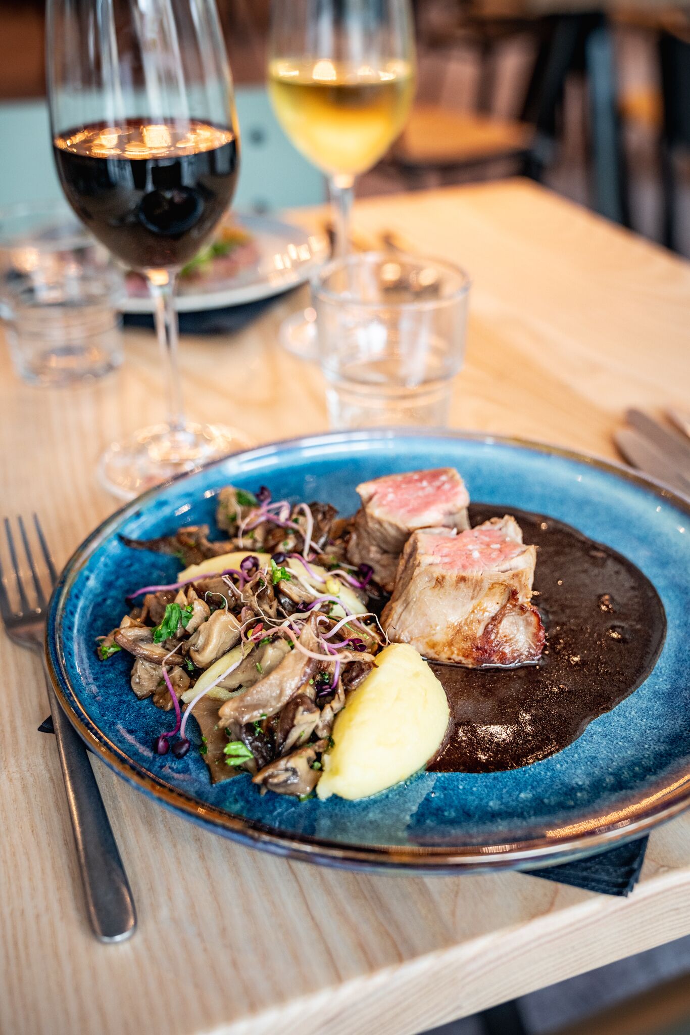 A plate of food with mushrooms, a slice of meat, and a dollop of sauce on a blue plate.