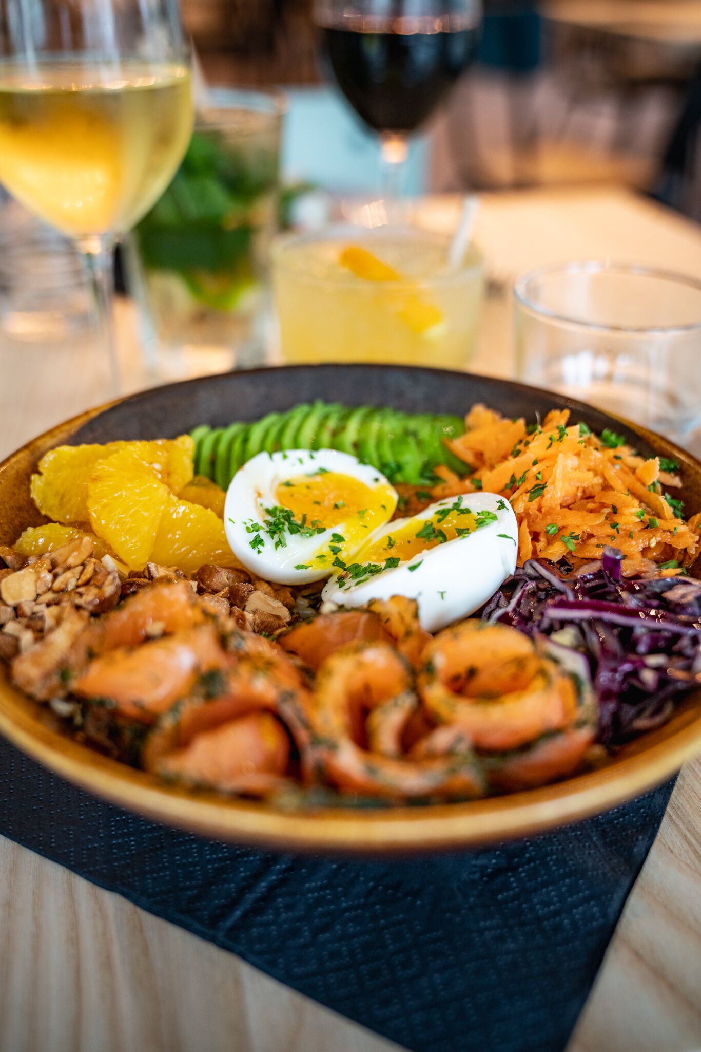 A bowl of seafood salad with shrimp, eggs, and vegetables on a wooden table.