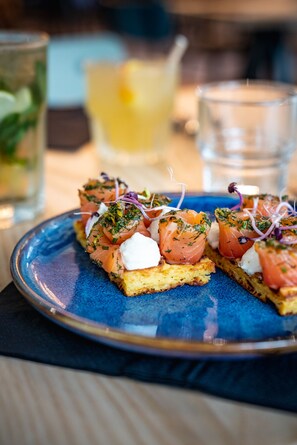 A plate of appetizers with smoked salmon, cream cheese, and herbs, accompanied by a glass of lemonade. - ibis Styles Limoges Centre (Limoges)