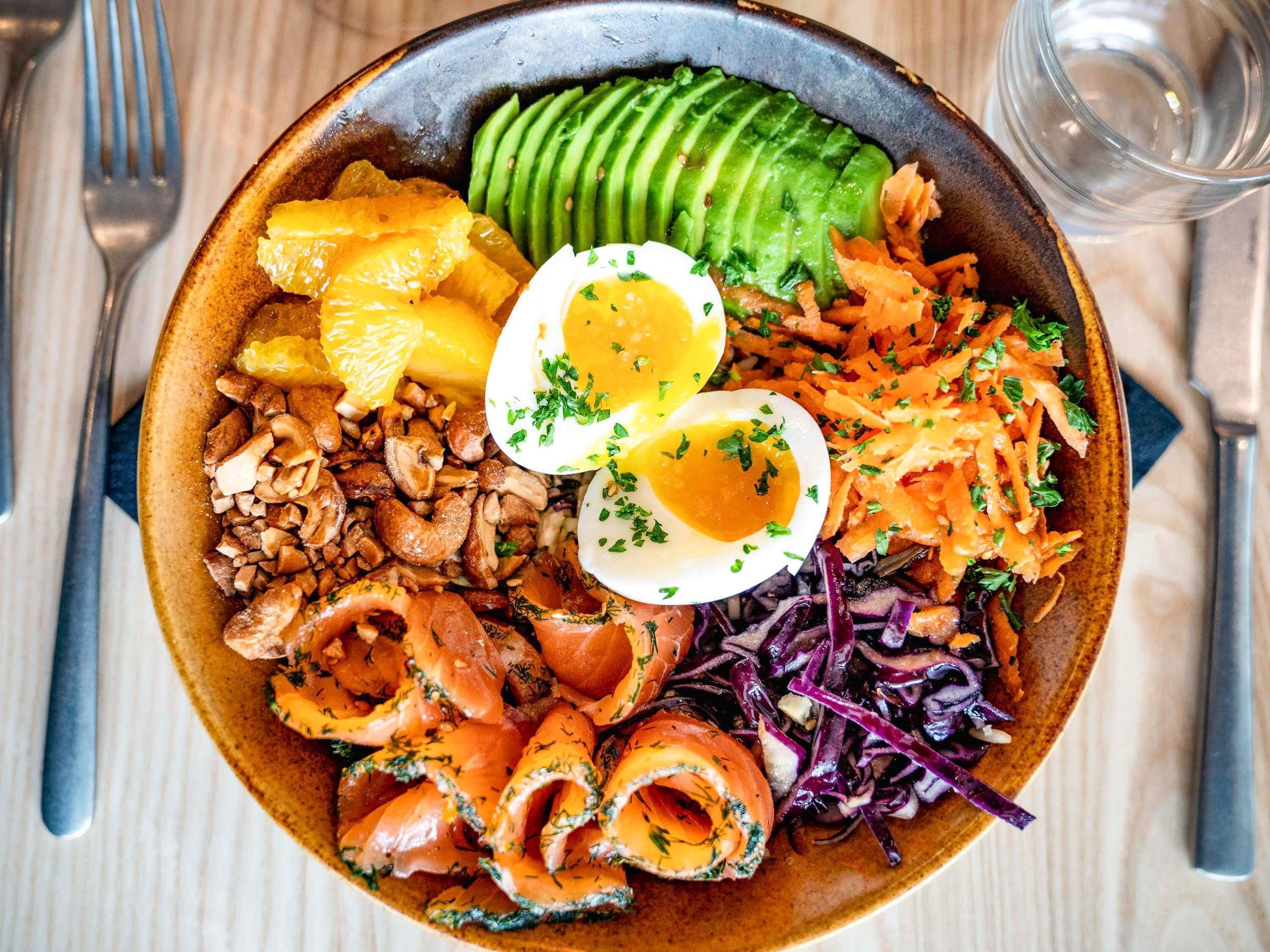 Comida con varios ingredientes, entre ellos aguacate, huevos y verduras.