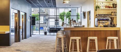 Un área de bar moderna con taburetes, una barra y una máquina de café.