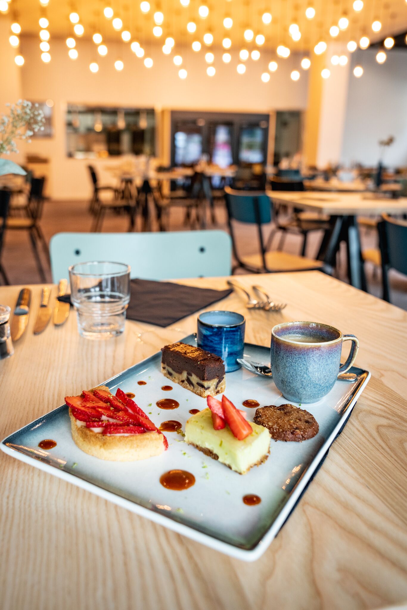 A dining table with a dessert plate, a blue mug, and a glass of water.