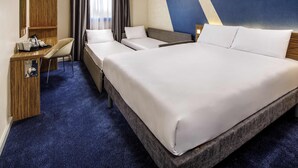 A hotel room with a large bed, a desk with a chair, a small table with a tray, and a mirror. - Ibis Budget Heathrow Terminal 5 (Slough)