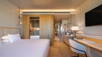 Habitación de hotel con una cama grande, un escritorio, una silla, un televisor y un baño con ducha.