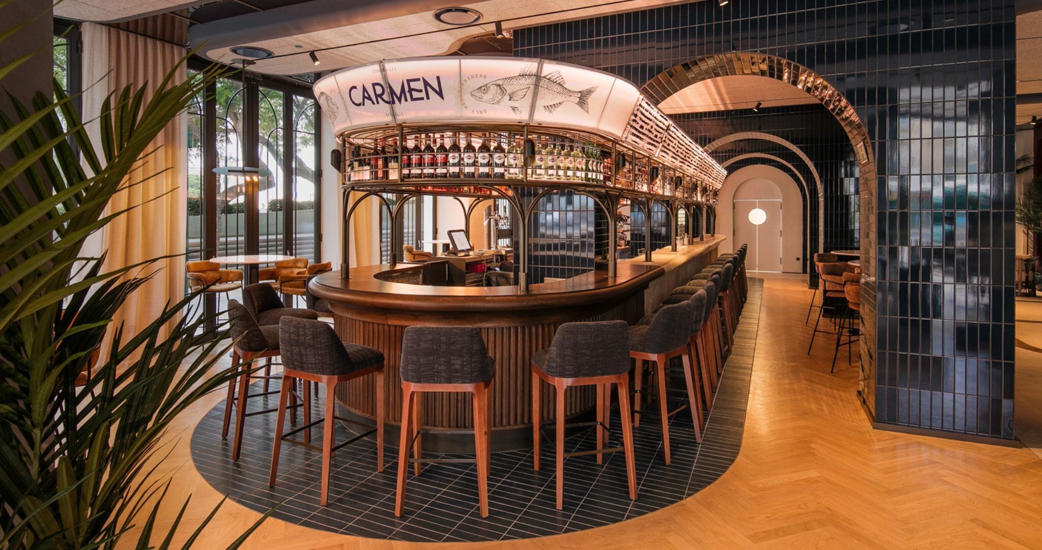Una zona de bar con un mostrador curvo, varios taburetes y un letrero que dice 'CARMEN'.