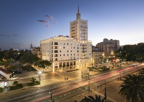 A multi-story hotel with a prominent tower, a well-lit facade, and a busy street with light trails indicating traffic. - Only YOU Hotel Malaga (Málaga)