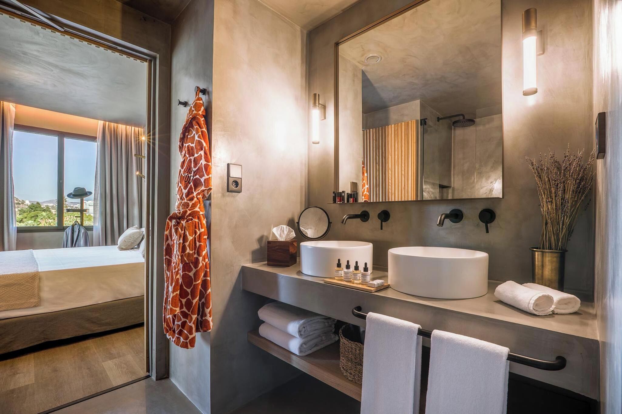 A modern bathroom with a large mirror, two sinks, and a view of the outdoors.
