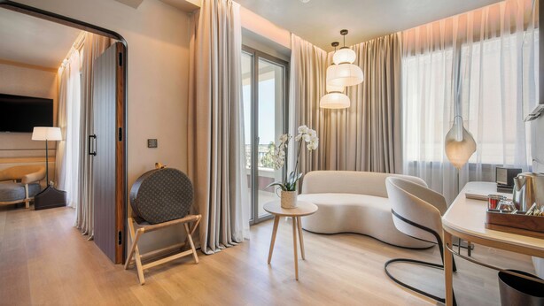 Une chambre d’hôtel moderne avec un canapé, une table ronde, une lampe et un téléviseur.