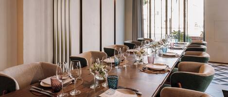 Una larga mesa de comedor dispuesta con numerosas sillas, vasos, cubiertos y una carta.