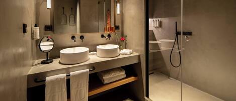 Une salle de bain moderne avec deux lavabos, un grand miroir et une douche à parois de verre.
