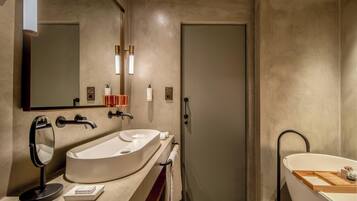 A modern bathroom with a large oval sink, a separate bathtub, and a door with a handle.