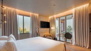 Une chambre d’hôtel avec un grand lit, un téléviseur à écran plat, un fauteuil et une vue sur l’extérieur.