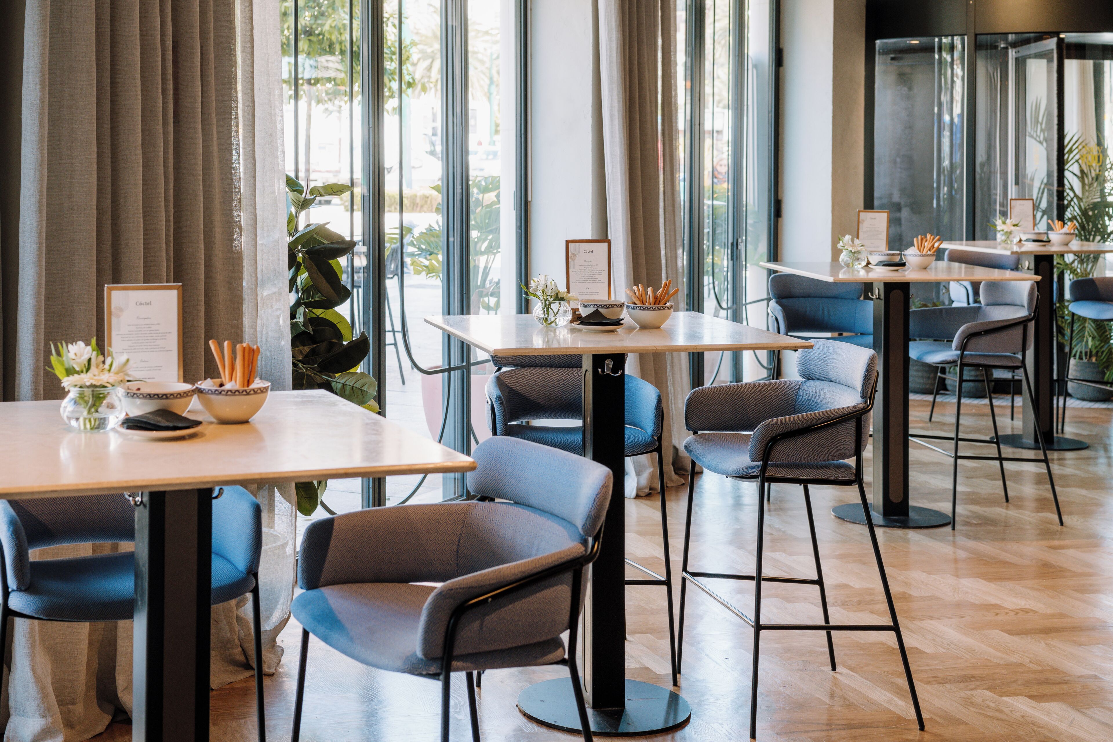 En modern restaurang med höga bord, stolar och stora fönster.