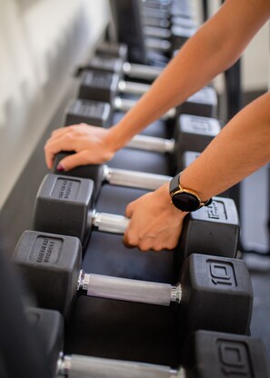 A close-up of hands adjusting weights on a barbell. - Only YOU Hotel Malaga (Málaga)