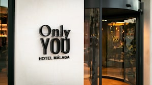 L’entrée d’un hôtel, avec une porte tournante et une enseigne indiquant : « Only You HOTEL MÁLAGA ».