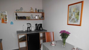 A compact kitchen with a dishwasher, coffee maker, and toaster. A dining table with plates and a vase of flowers is set. - Cozy vacation home 100 sqm in the middle of nature (Aerzen)