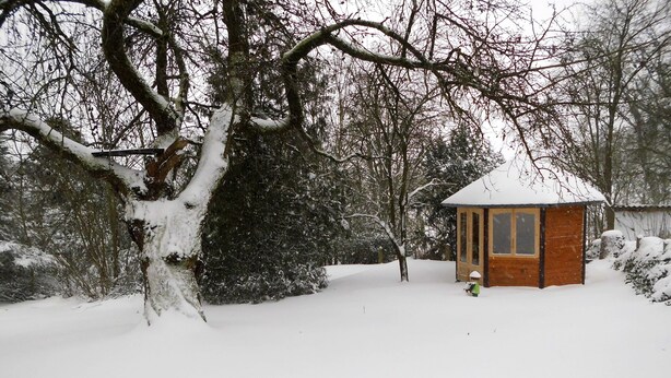 A wooden cabin with a snow-covered roof, surrounded by trees and a snowy landscape. - Cozy vacation home 100 sqm in the middle of nature (Aerzen)