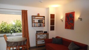 A living room with a red sofa, a wooden coffee table, and a bookshelf. - Cozy vacation home 100 sqm in the middle of nature (Aerzen)