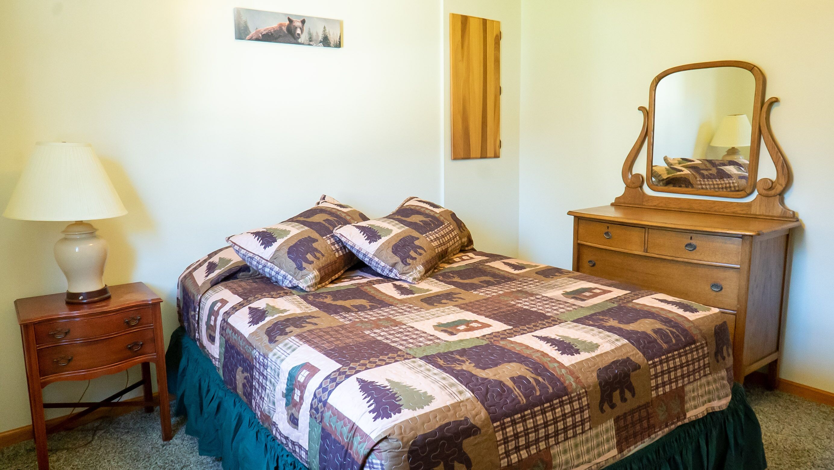 Une chambre à coucher avec un lit, une commode, une lampe et un miroir.
