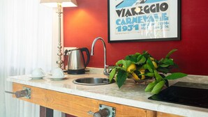 A kitchen counter with a kettle, a sink, and a potted plant.