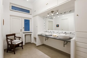 A bathroom with two sinks, a large mirror, and a chair with towels. - Villa Gallone: First Love (SORRENTO)