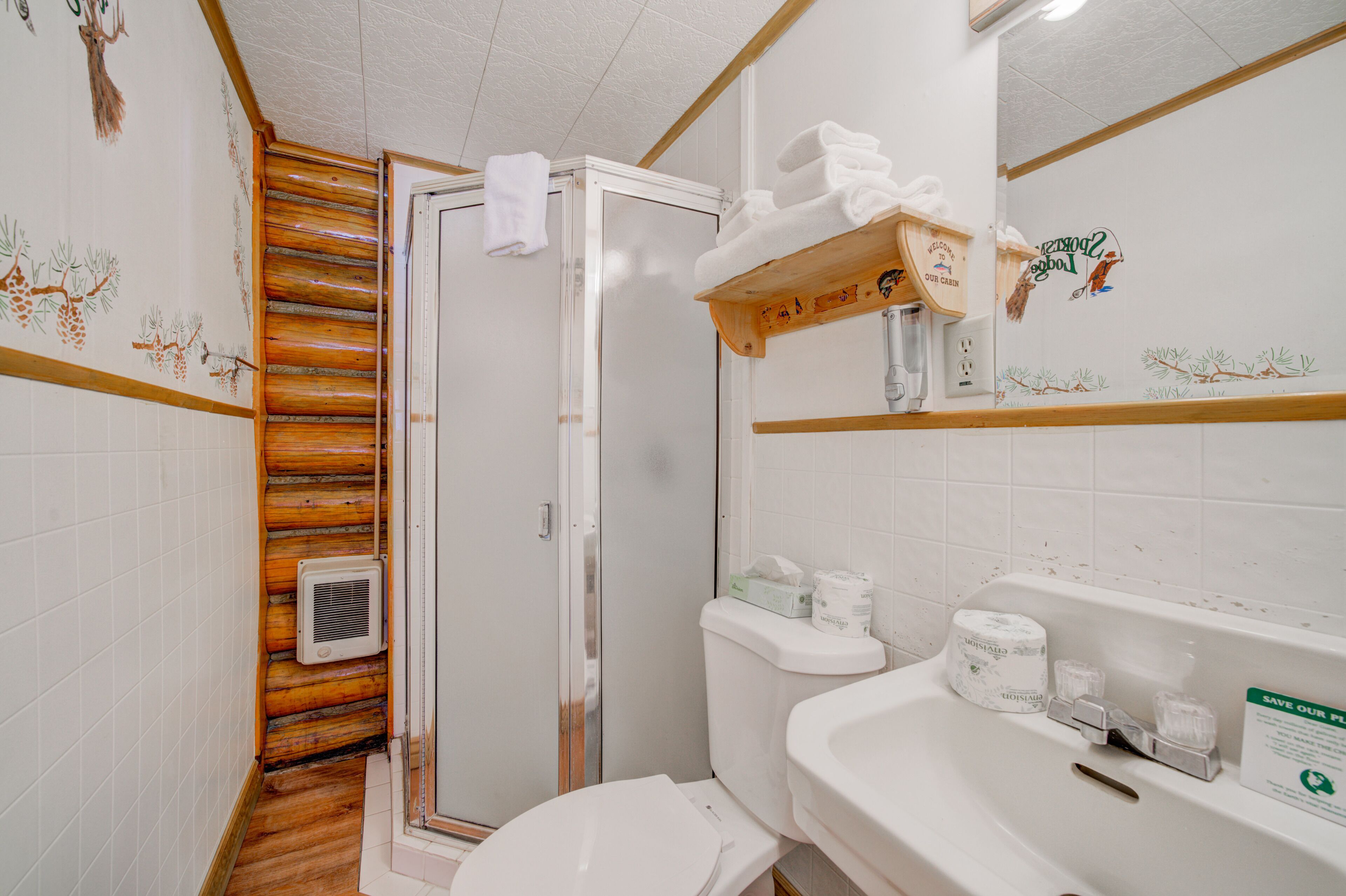 Un baño con cabina de ducha de madera, inodoro, lavabo con artículos de aseo y toallero.