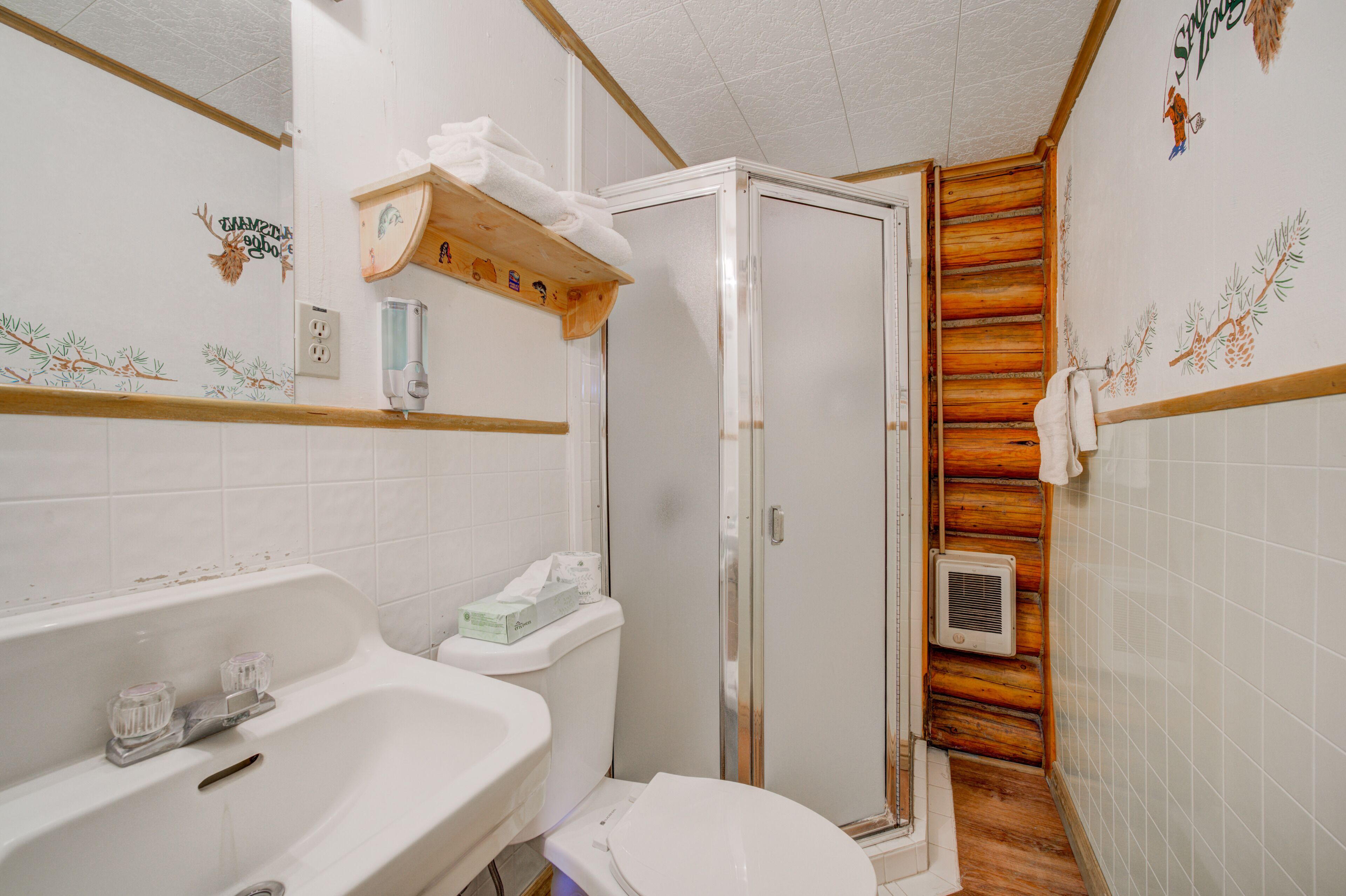 Casa de banho com chuveiro, sanita, lavatório e suporte para toalhas.