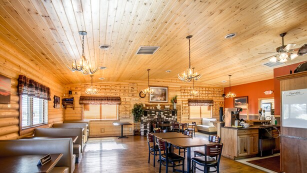A log cabin interior with wooden walls, a dining area, and a kitchen. - Sportsmans Lodge (Ennis)