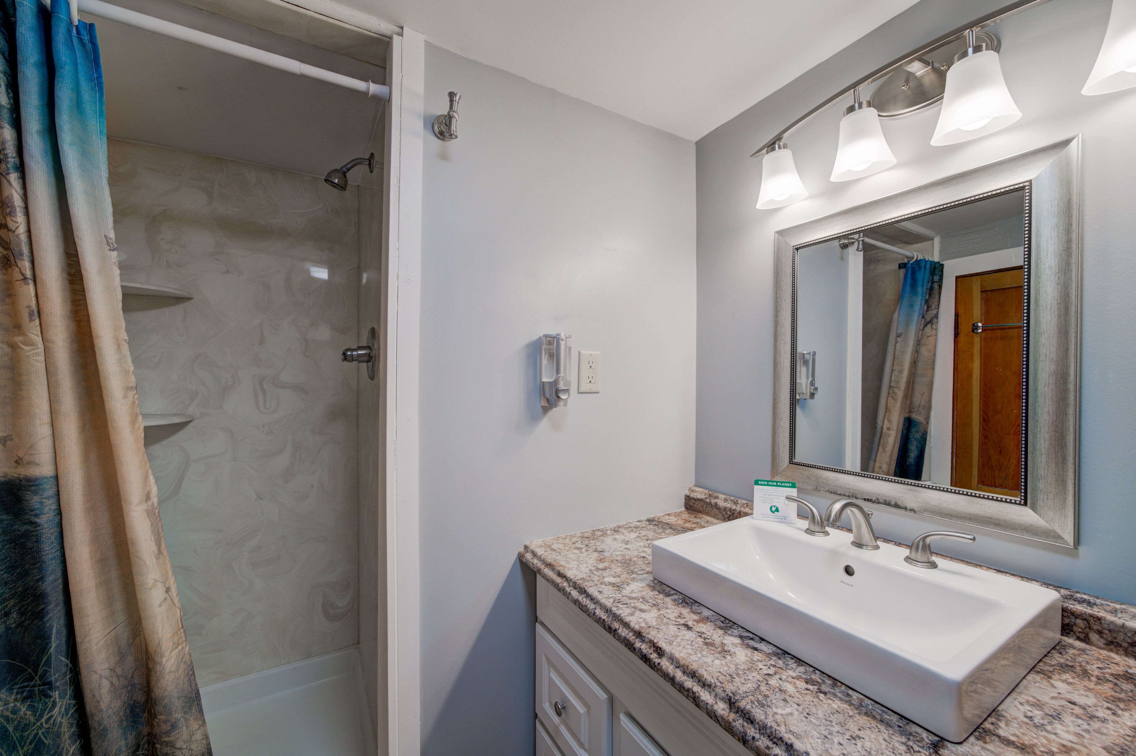 A bathroom with a white sink, a large mirror, and a shower area.