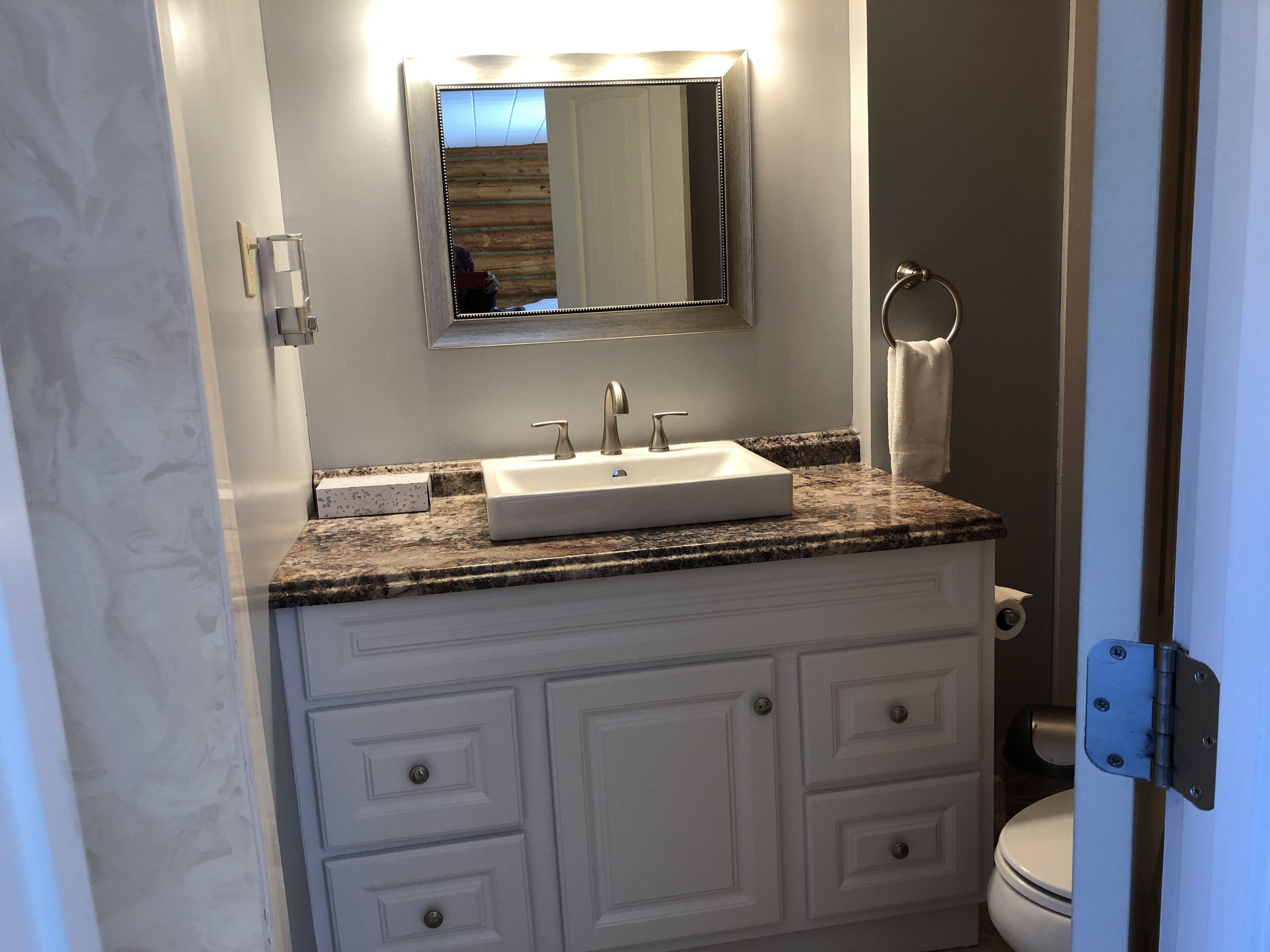 A bathroom with a white sink, a mirror, and a toilet.
