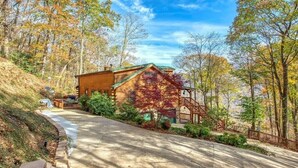 A log cabin with a green roof, a wooden staircase, and a paved driveway. - Linda's Haven - 3BR, 3 BA, Views, HT, FP, Game Room (Maggie Valley)
