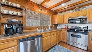 A kitchen with wooden cabinets, stainless steel appliances, a coffee maker, and a dishwashing machine.