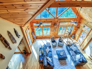 Cozy cabin with a large seating area, fireplace, and forest views.
