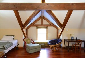 Une chambre mansardée chaleureuse avec un plafond en pente, un lit, une chaise, une petite table et une fenêtre.