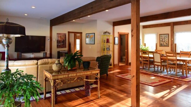 Un ampio soggiorno con una grande televisione, posti a sedere confortevoli e una zona pranzo con mobili in legno.