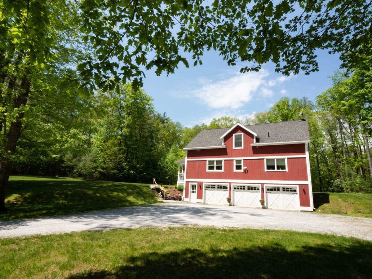 Une maison à deux étages, avec une façade rouge et des éléments décoratifs blancs, une allée et une pelouse bien entretenue.